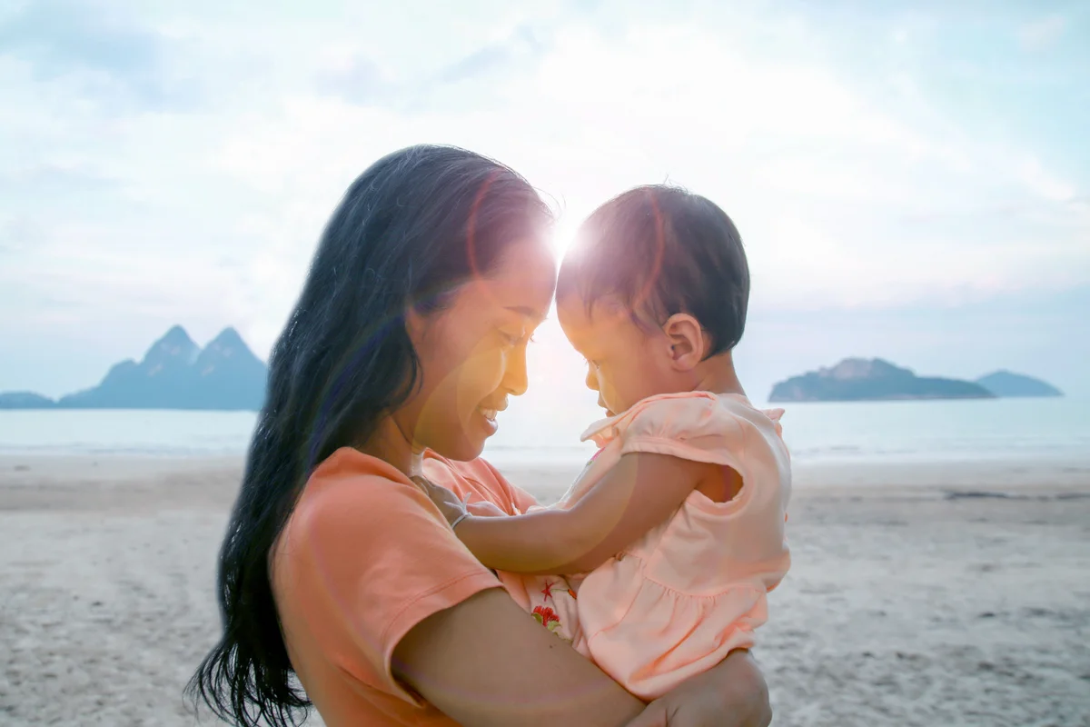 Mother And Daughter At Beach Against Sky