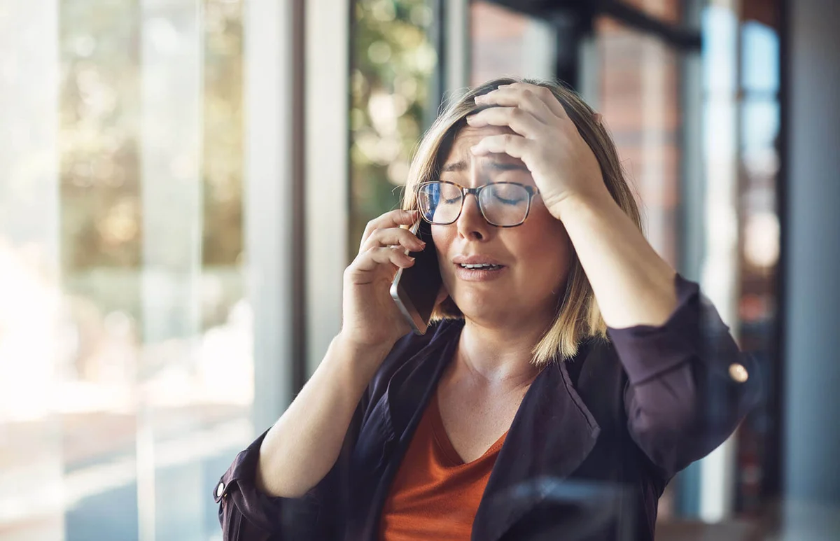 woman looking distraught while talking on a mobile phone