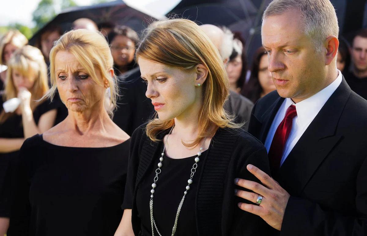 grieving family standing graveside at a funeral