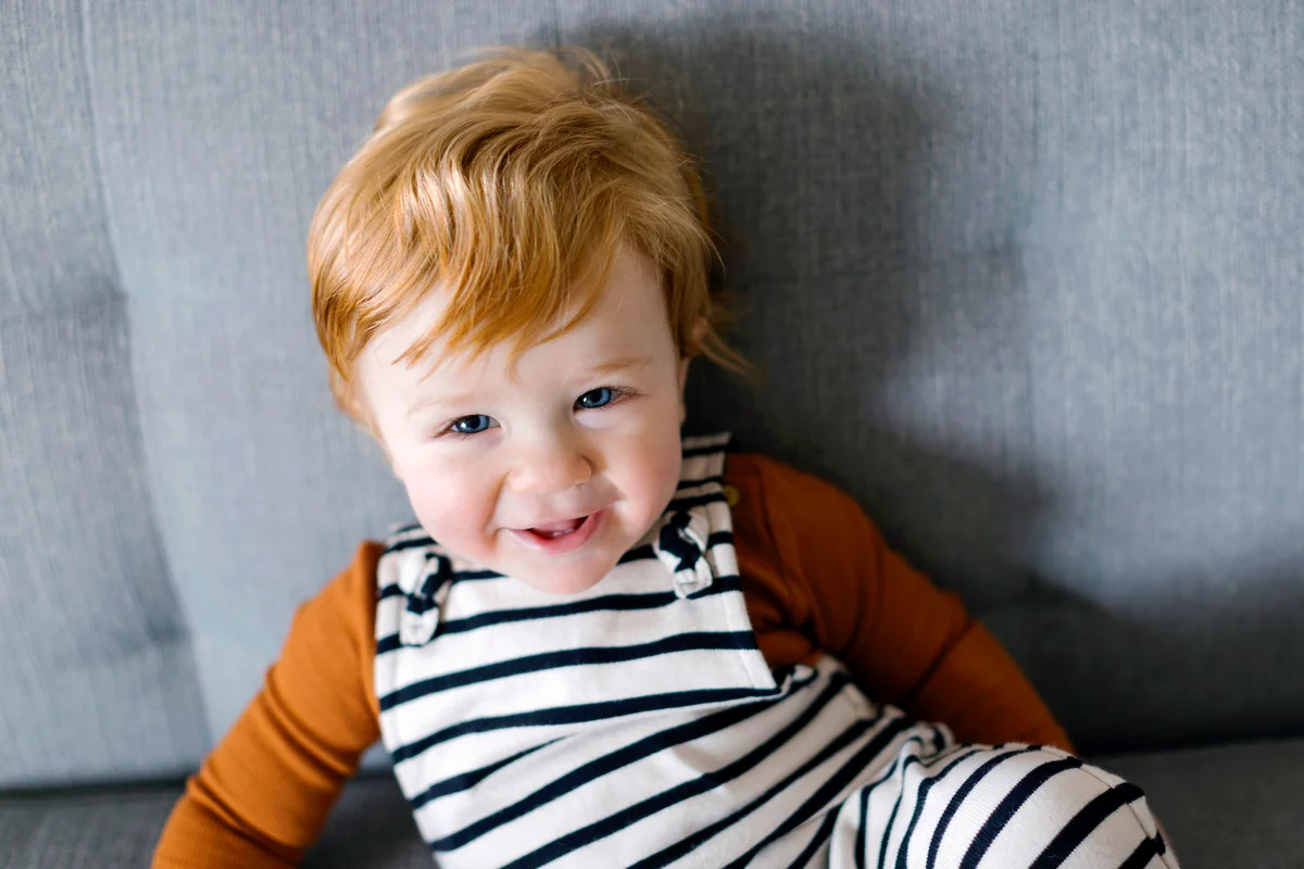 Smiling red haired baby boy on sofa