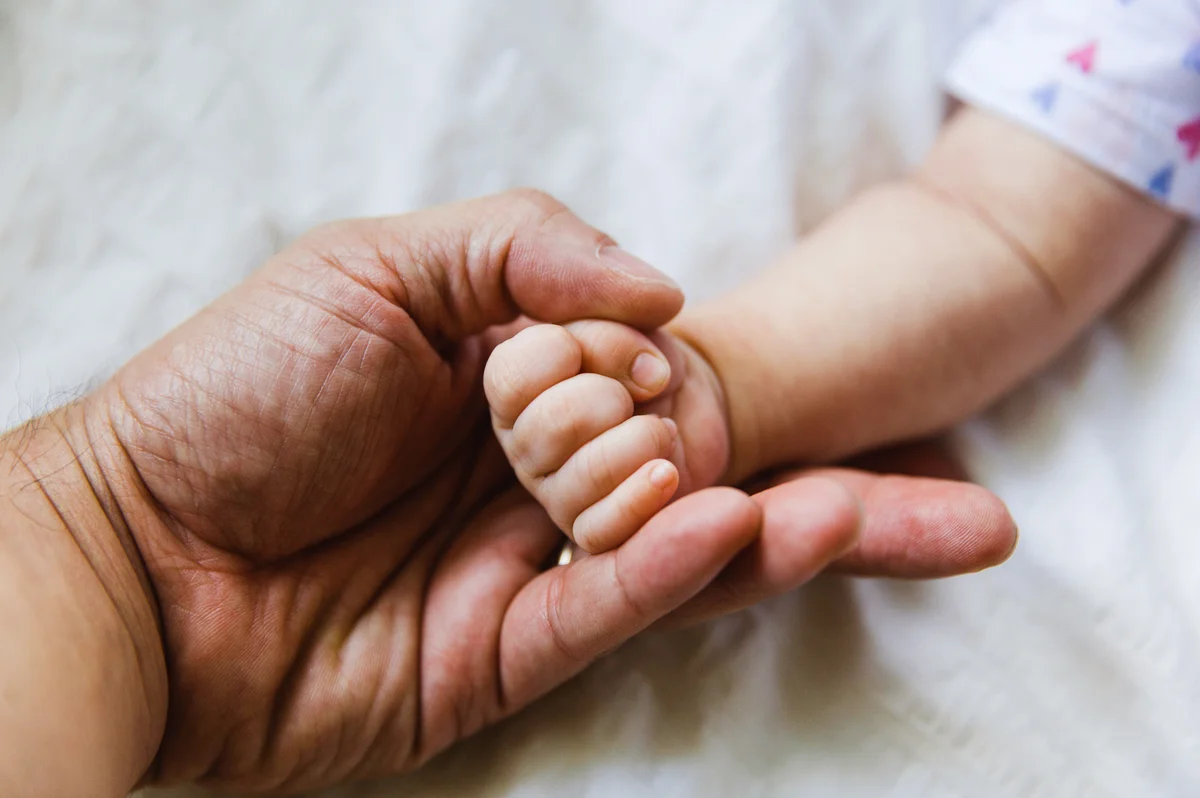 Baby fist resting on fathers hand
