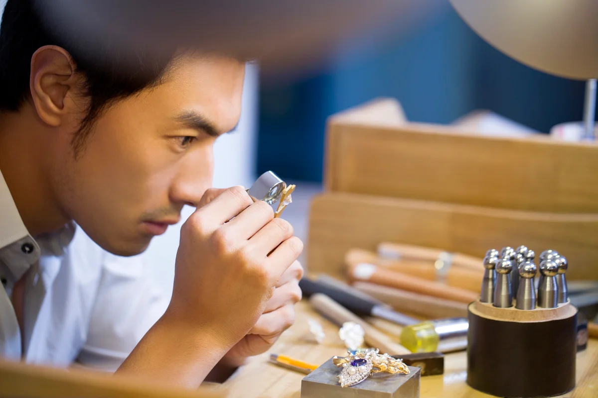 Male jeweller examining jewellery with loupe