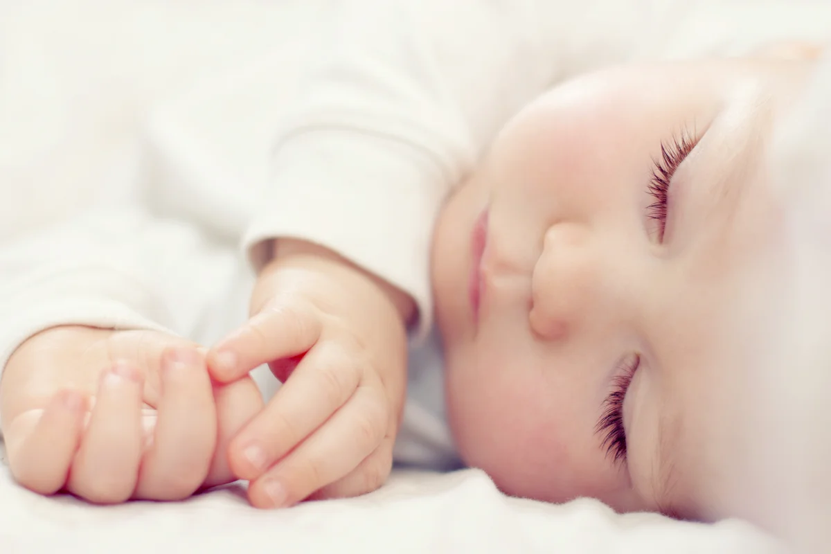 Beautiful sleeping baby on white bed