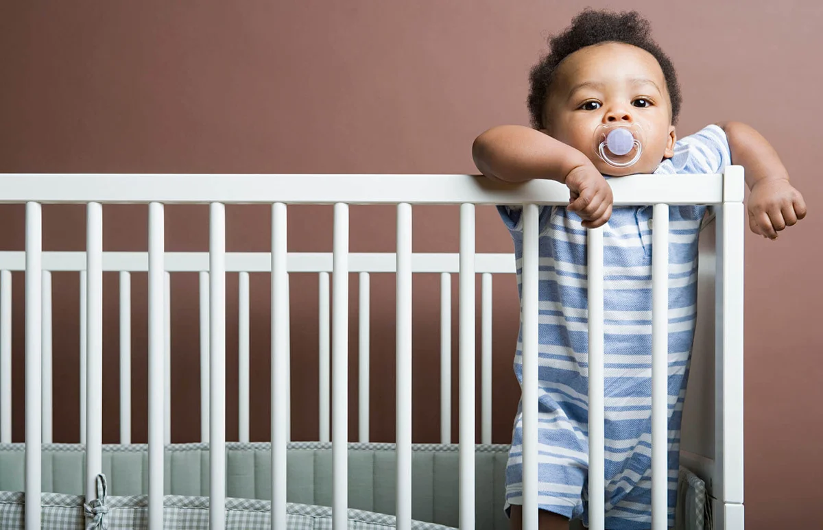 Baby boy standing in cot