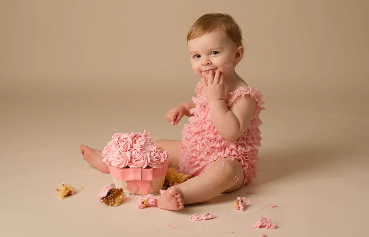 Baby smashing cake at first birthday in studio