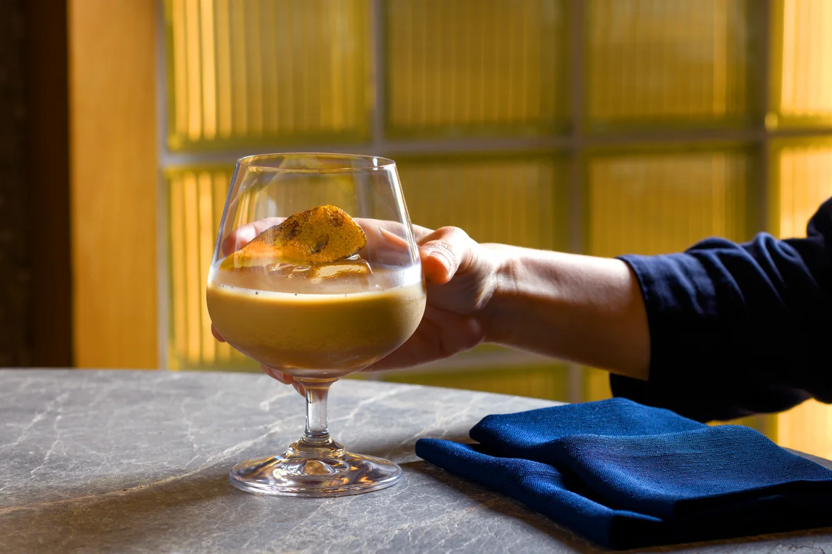 A hand holding a Baileys cocktail glass