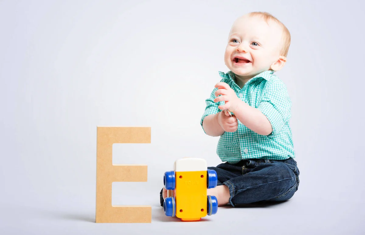 Baby Smiling on White with Wooden Letter and Toy