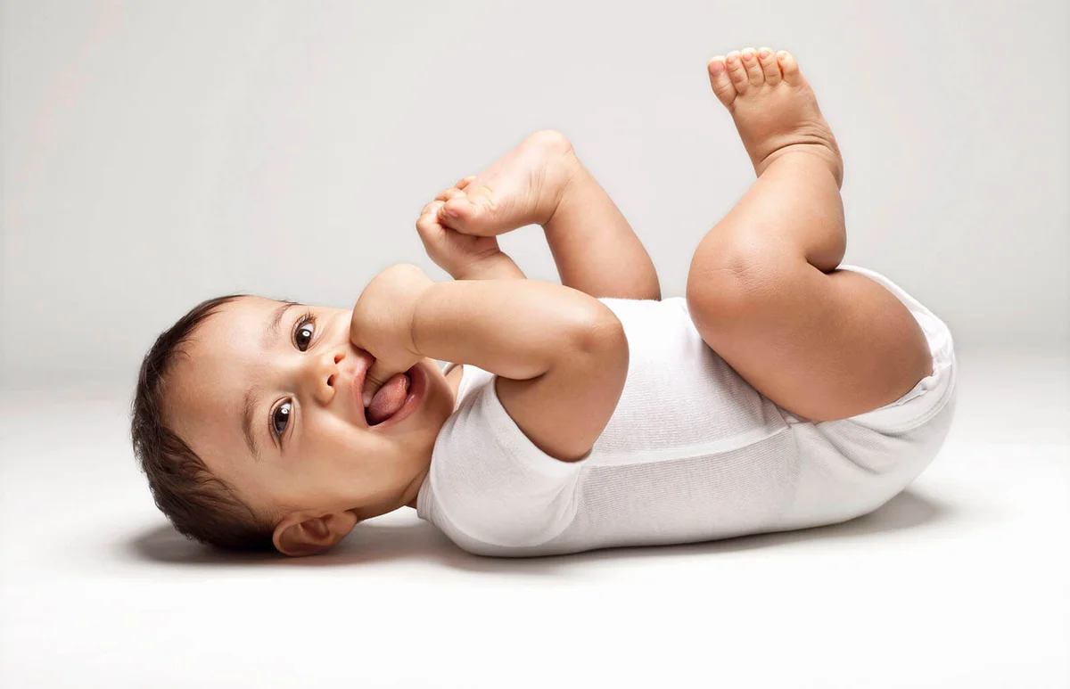 Baby boy laying on back with thumb in mouth