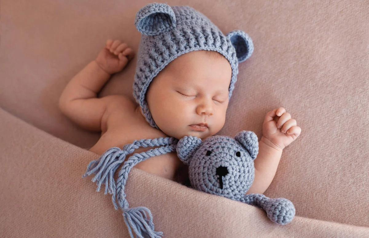Cute newborn baby sleeping with a teddy bear