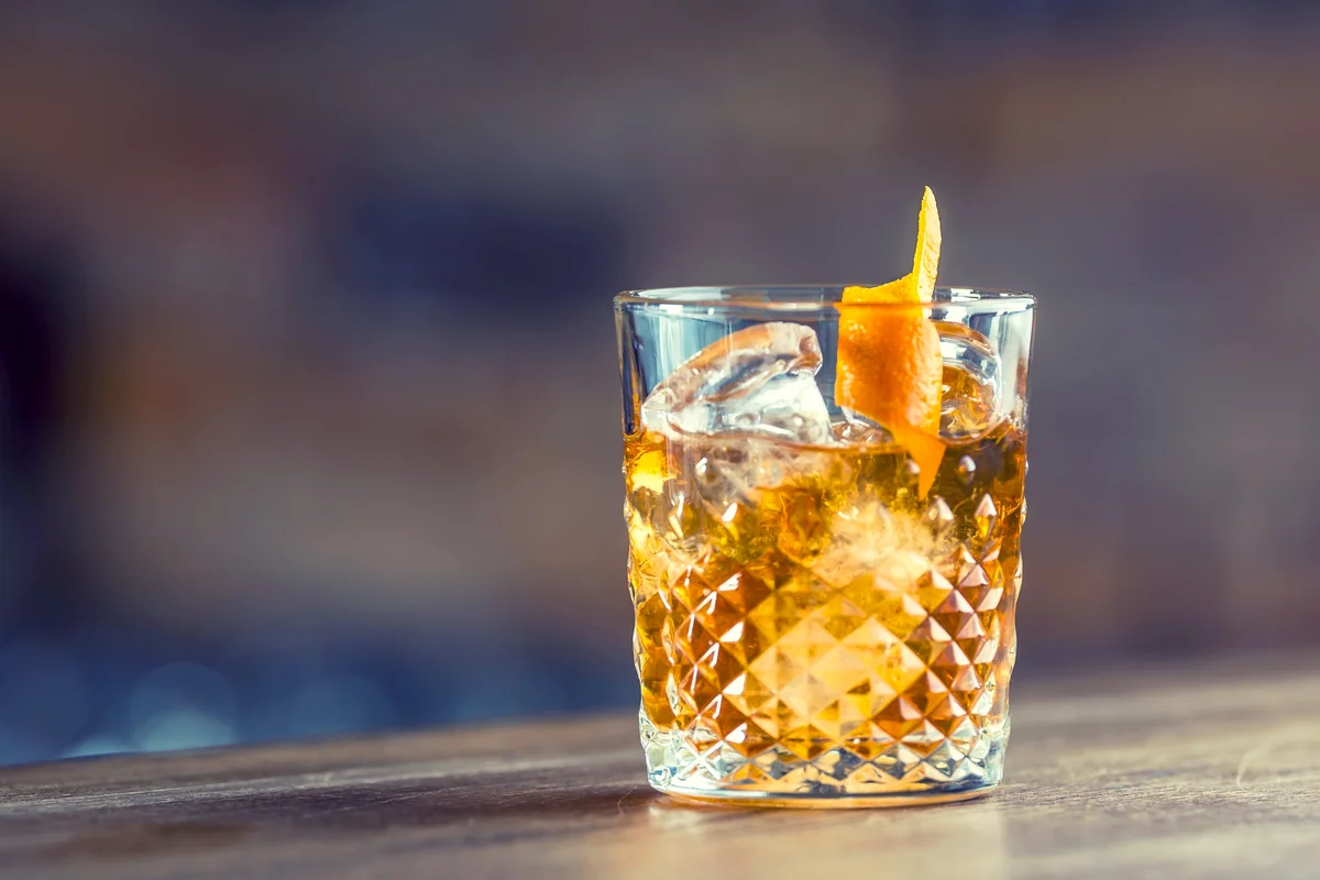 Old fashioned classic cocktail drink in crystal glass on bar counter