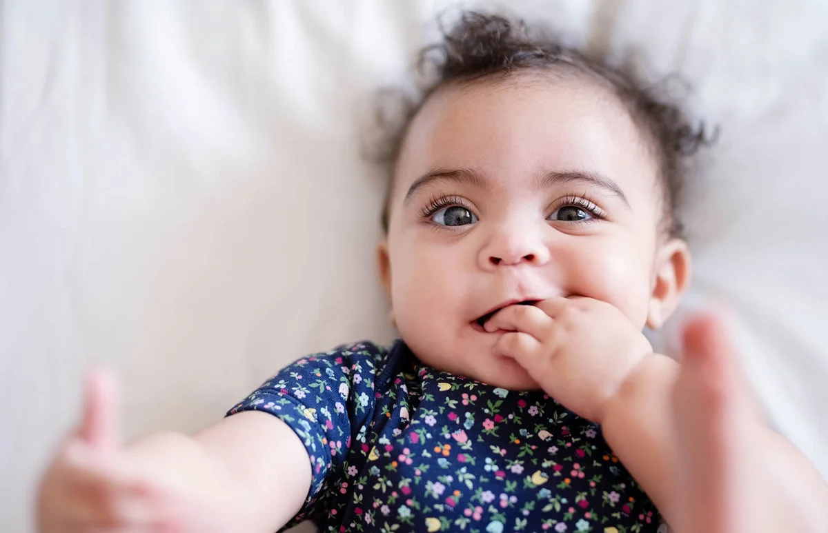 baby girl lying on bed and playing with her toes