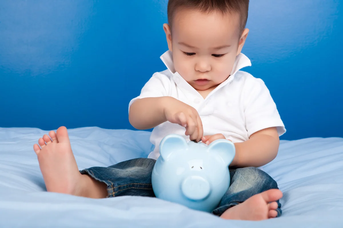 Boy putting money in blue piggy bank