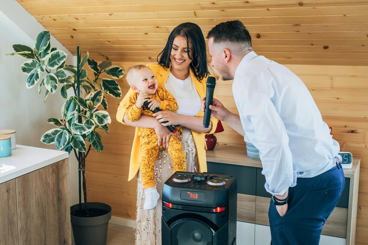 Happy family with their baby son, singing and dancing at home