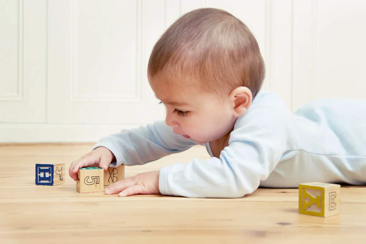 Baby lying on front playing with building blocks