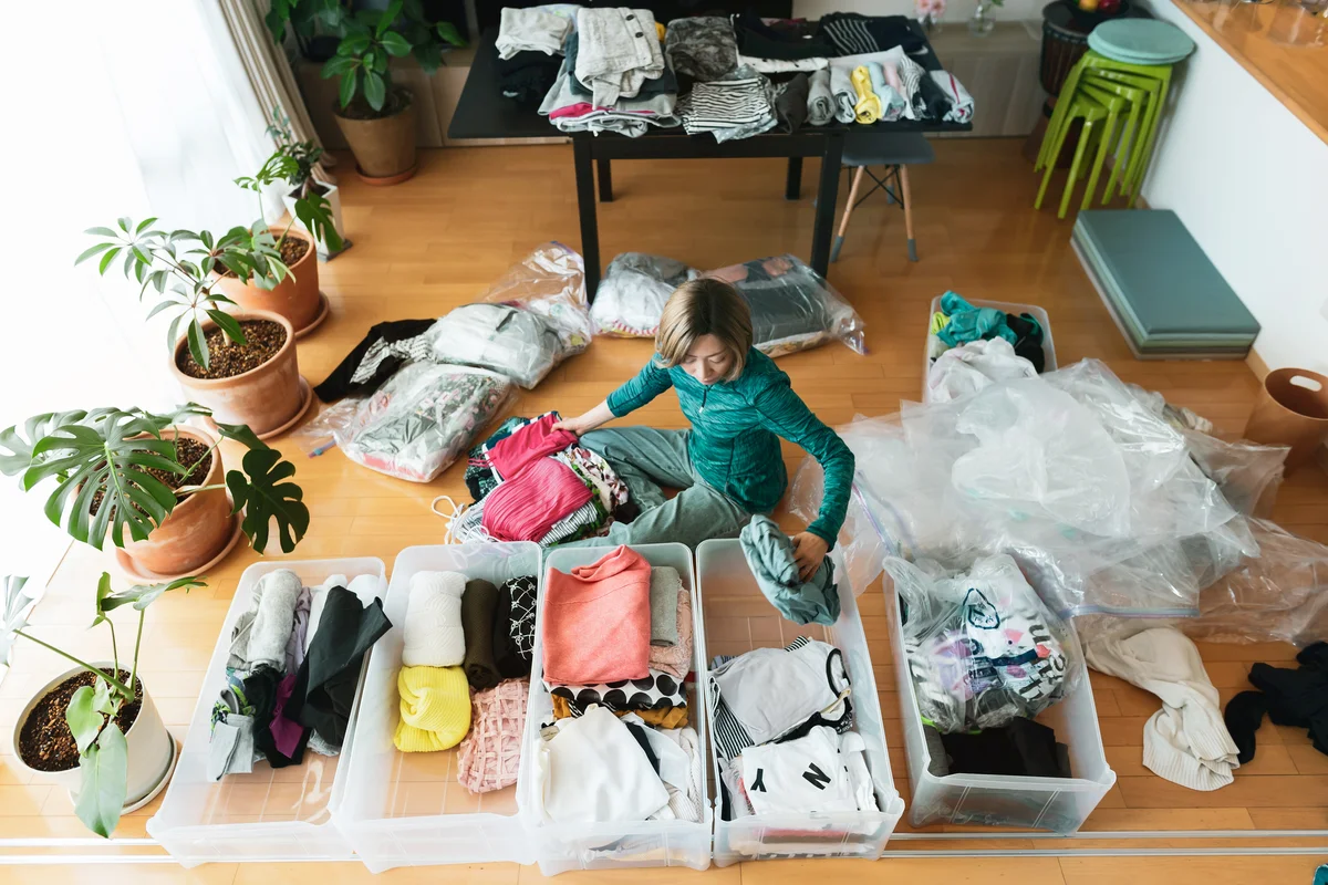 Woman organizes clothes in living room of her home