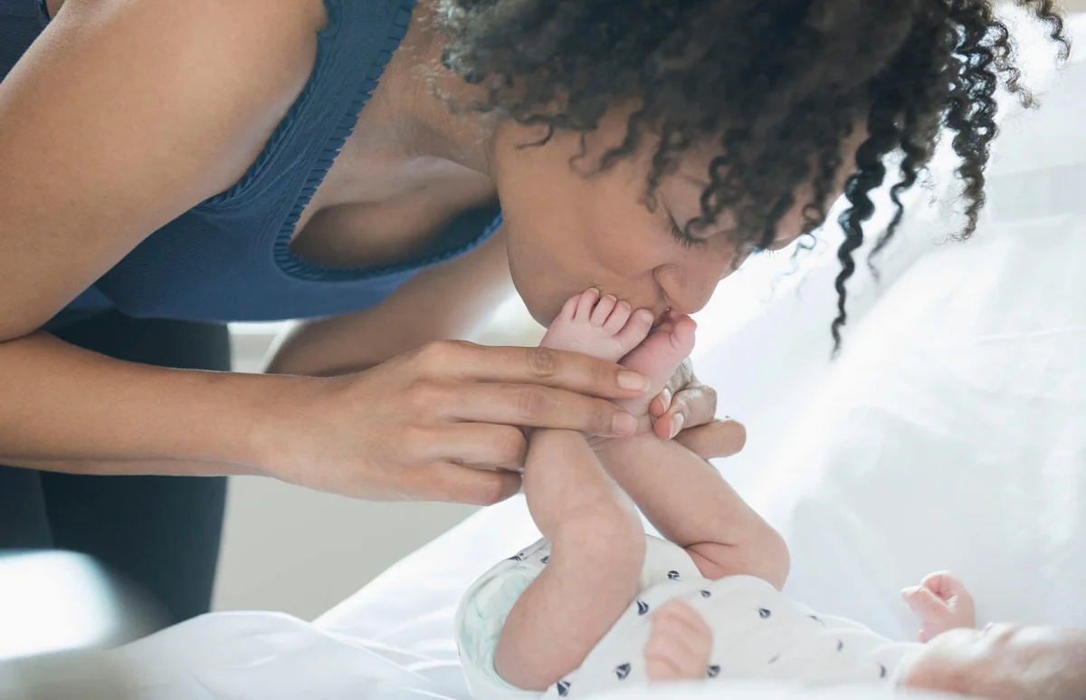mother kissing newborn baby feet