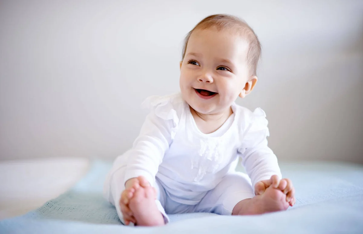 adorable baby girl sitting on a bed