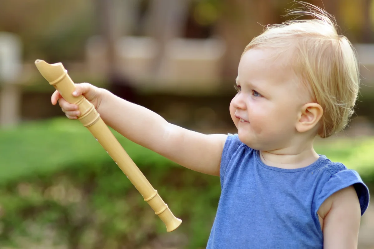 Little girl in blue dress with a flute in her hand in the park