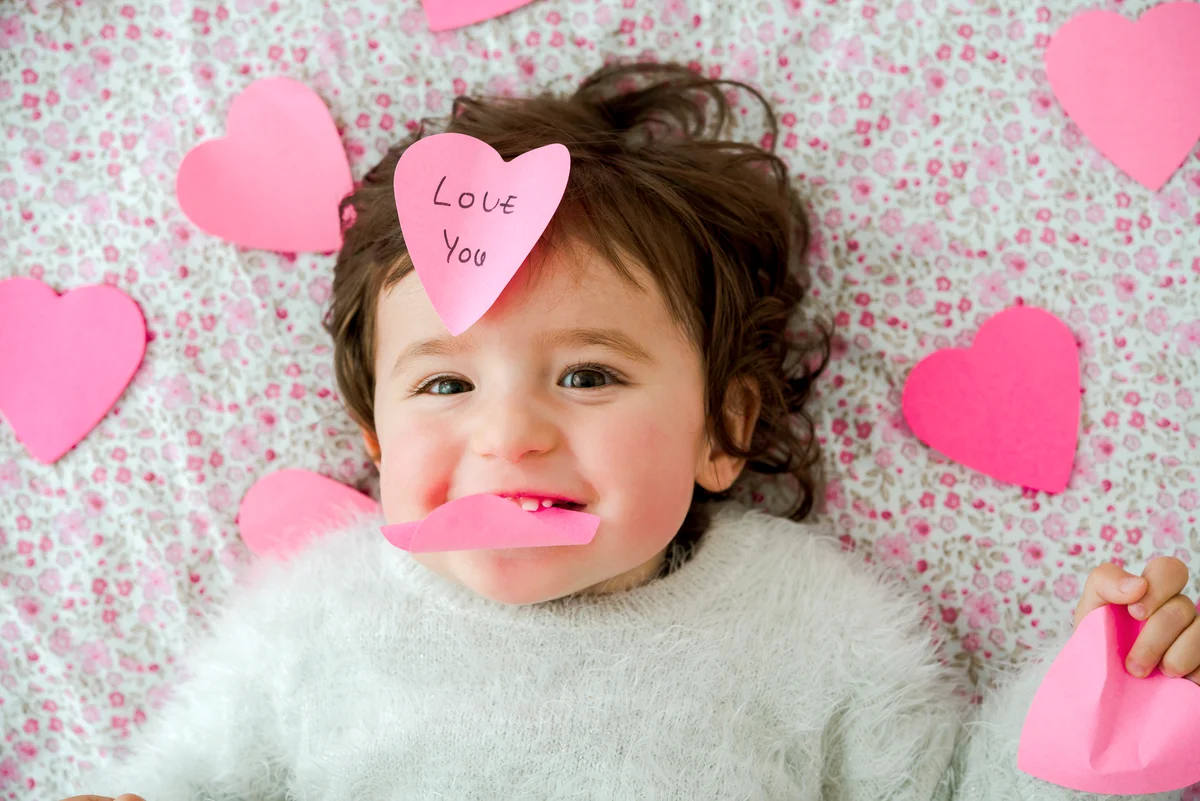 Baby girl with pink heart-shaped post it stickers