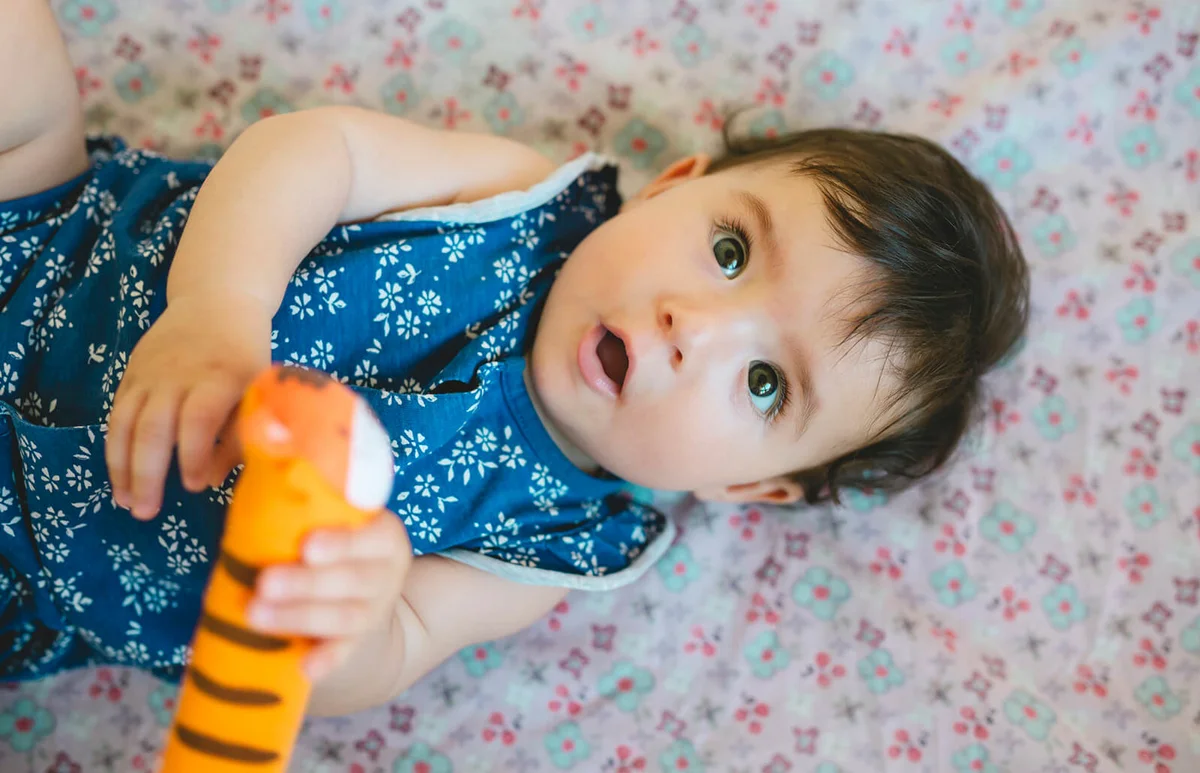 Baby girl playing with a tiger-shaped rattle