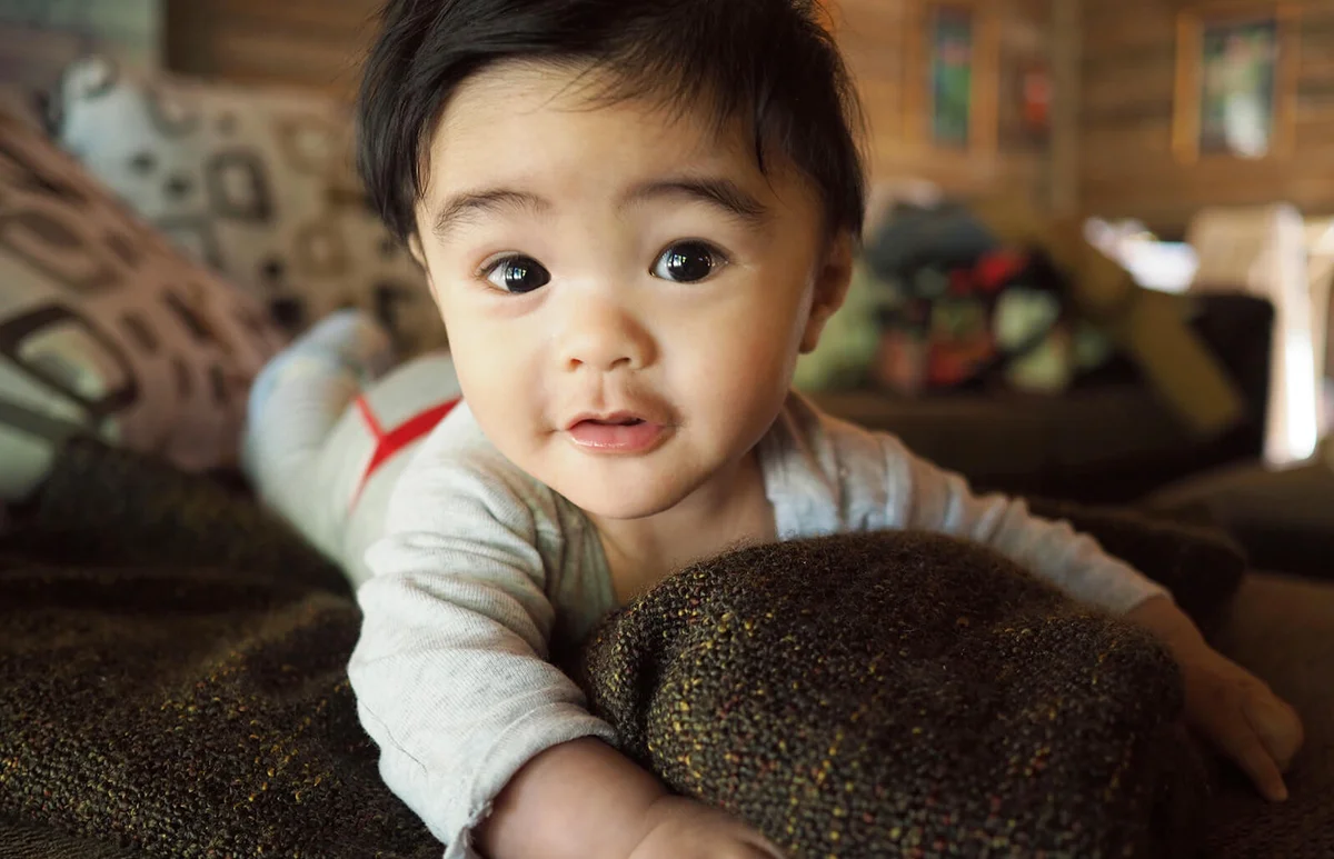 Cute five month old baby on sofa staring at camera