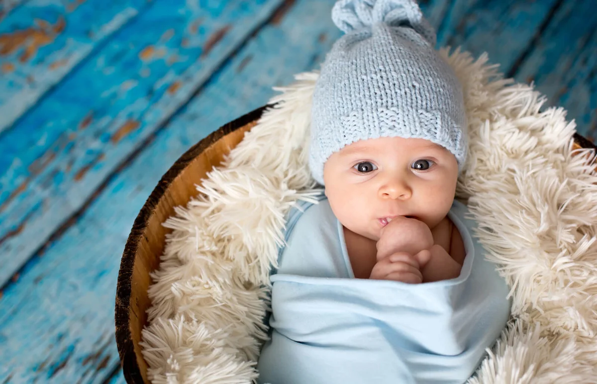 Little baby boy with knitted hat in a basket
