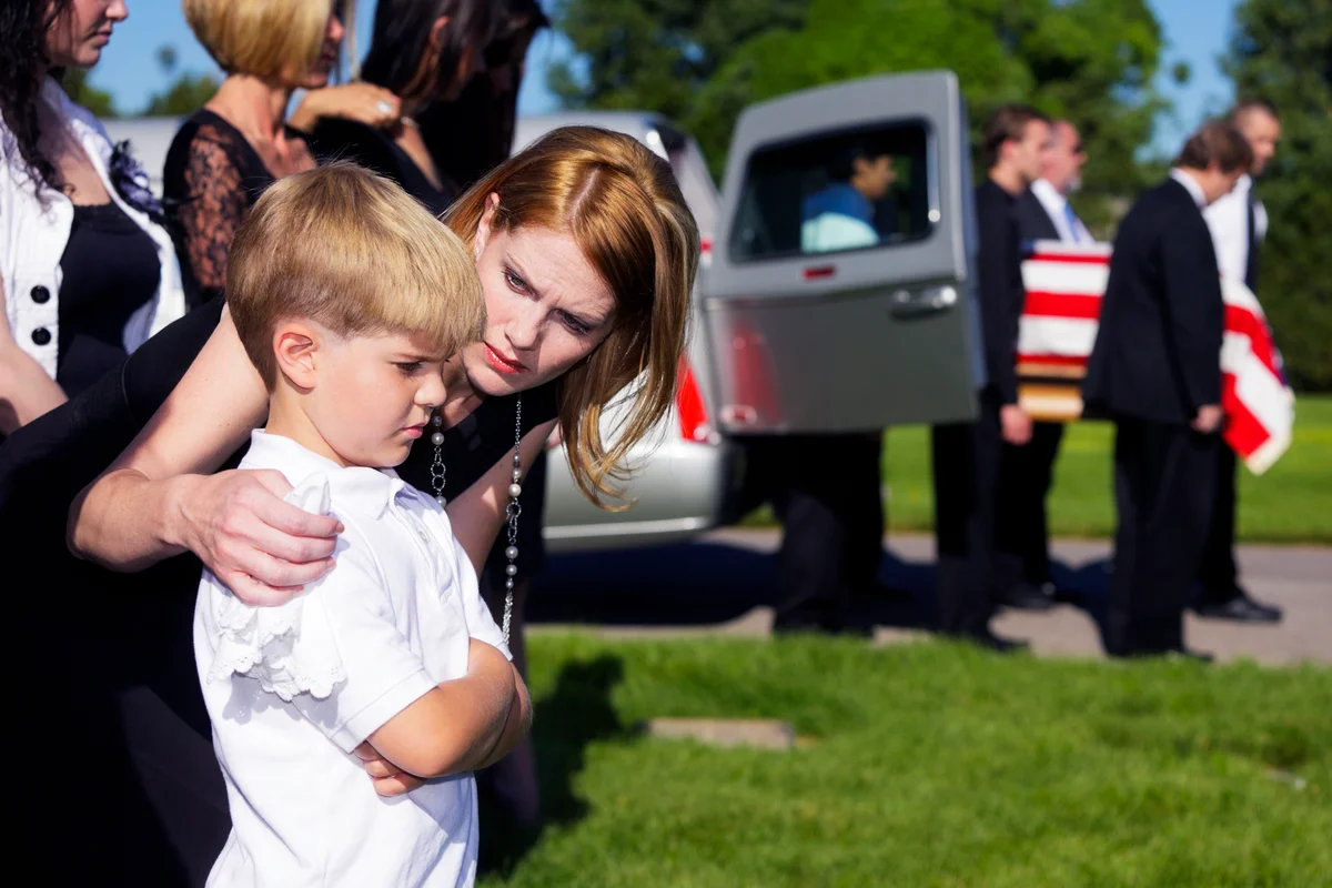 A mother comforting her son at a military funeral