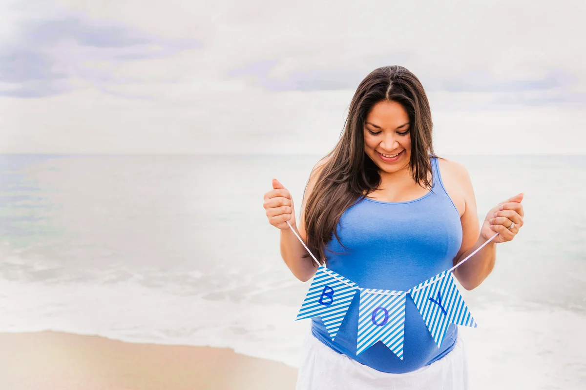 Pregnant woman holding boy banner on beach