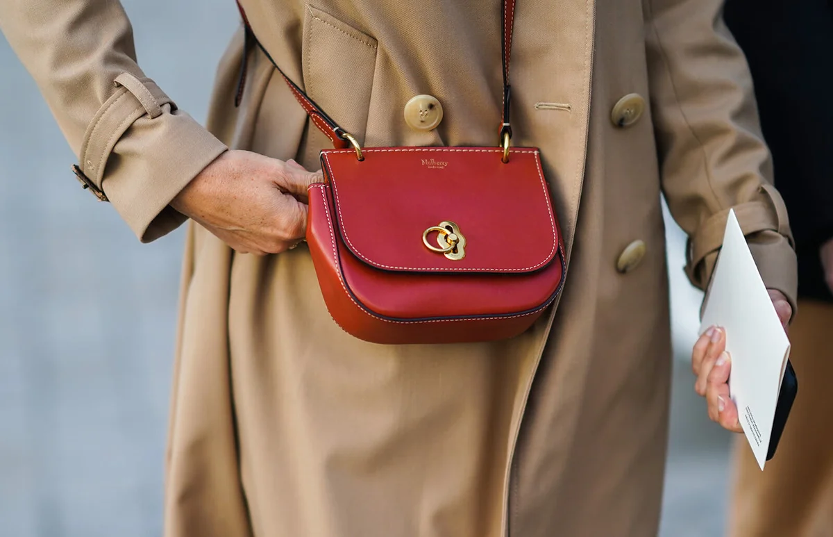 A guest wears a trench coat and a red Mulberry bag, outside Louis Vuitton, during Paris Fashion Week | Getty Editorial Use