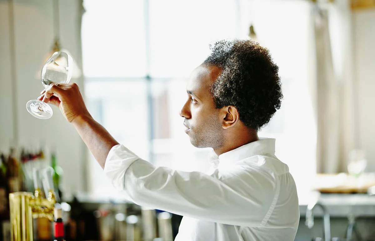 Bartender in restaurant examining wine glass
