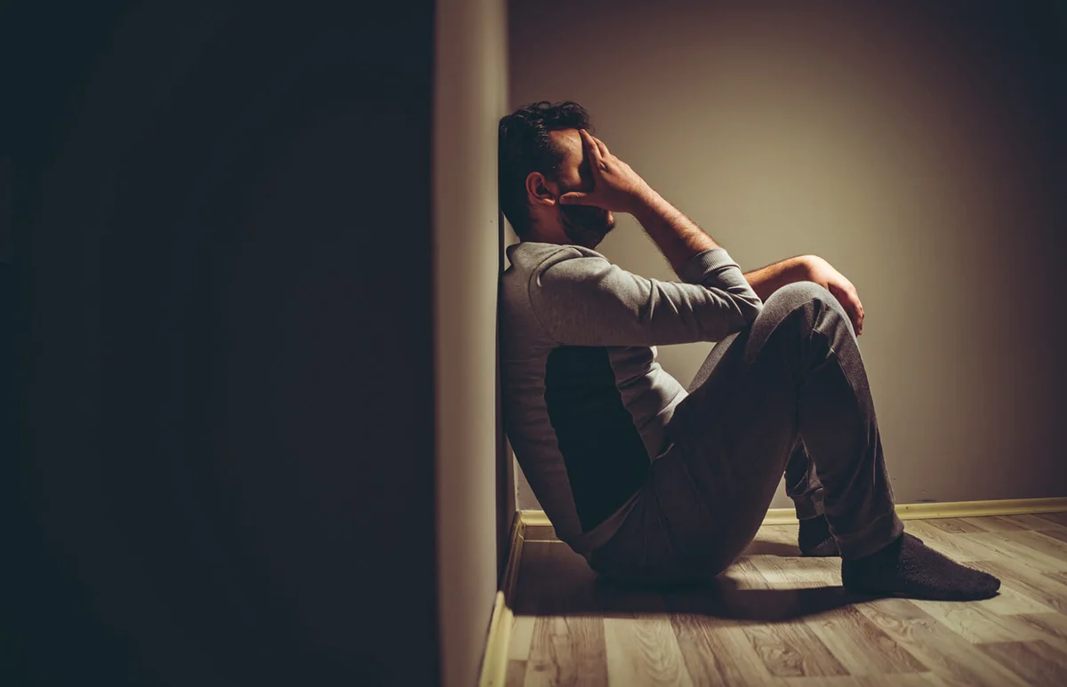 Young depressed man sitting on floor