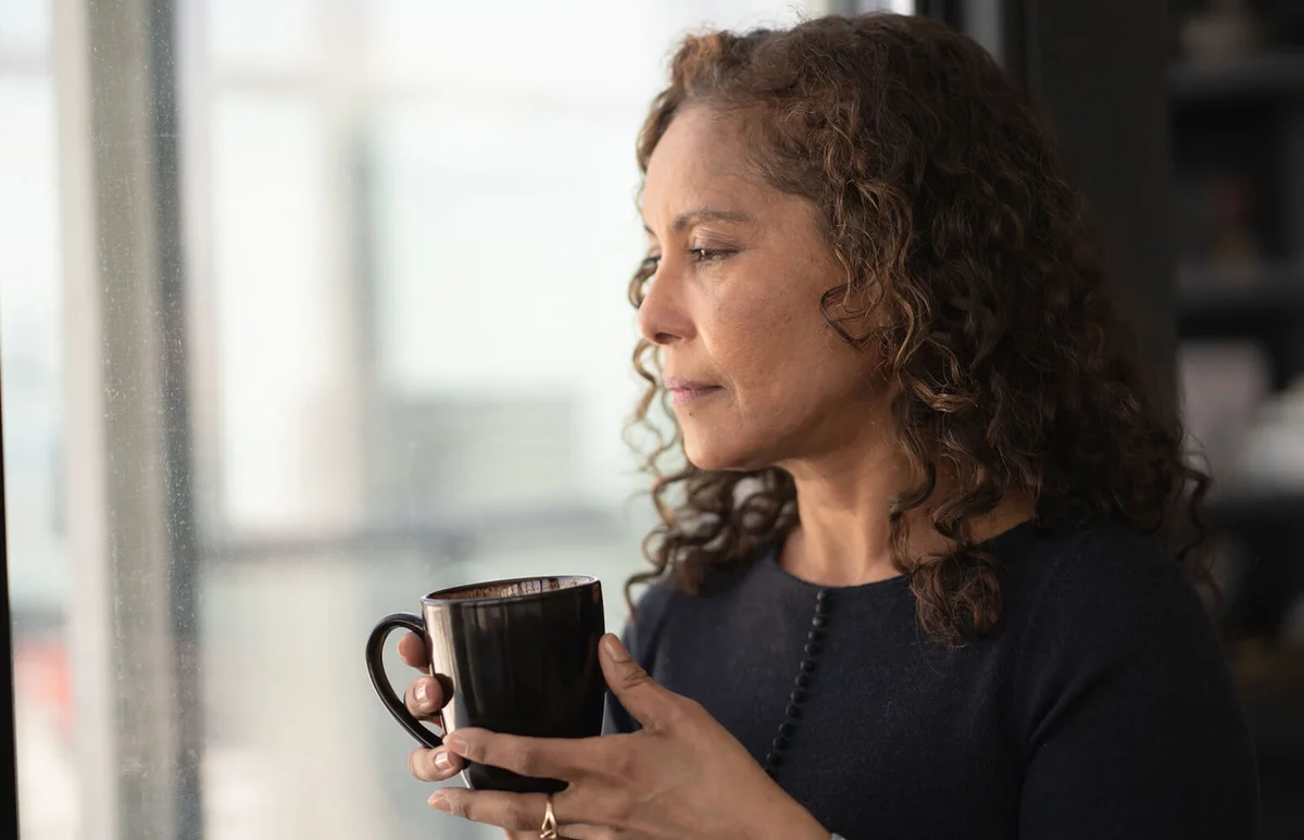 Portrait of a beautiful black woman drinking tea by window