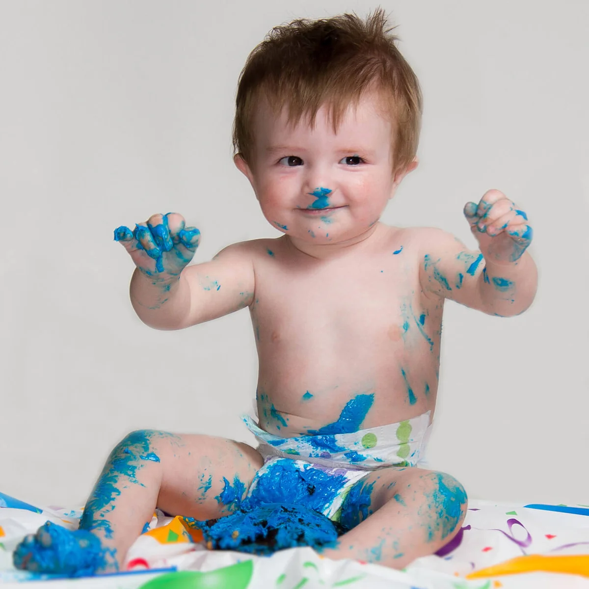 One year old little boy smashing and eating his birthday cake