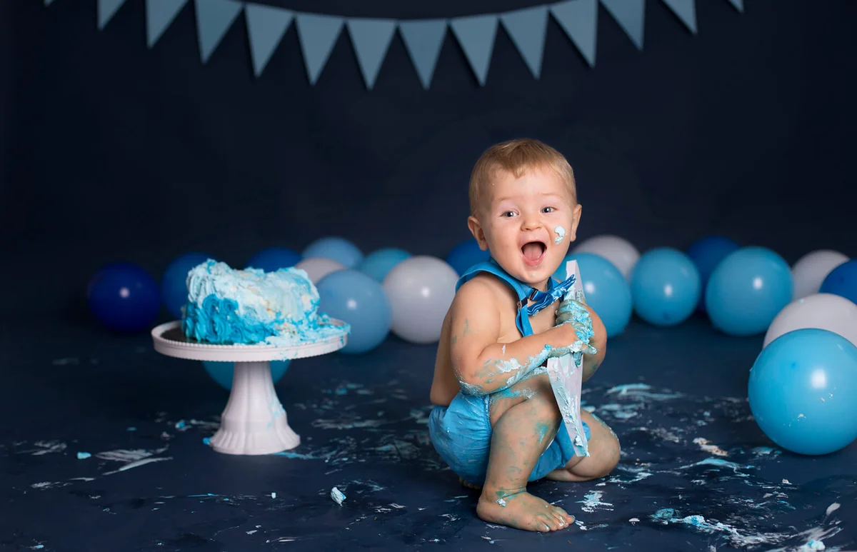 Baby boy playing with a cake during cake smash birthday party