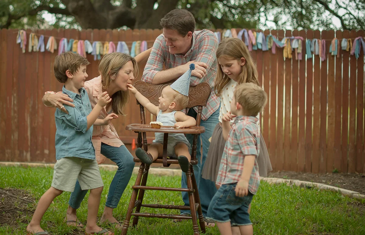 Family celebrating baby boys' first birthday in back yard