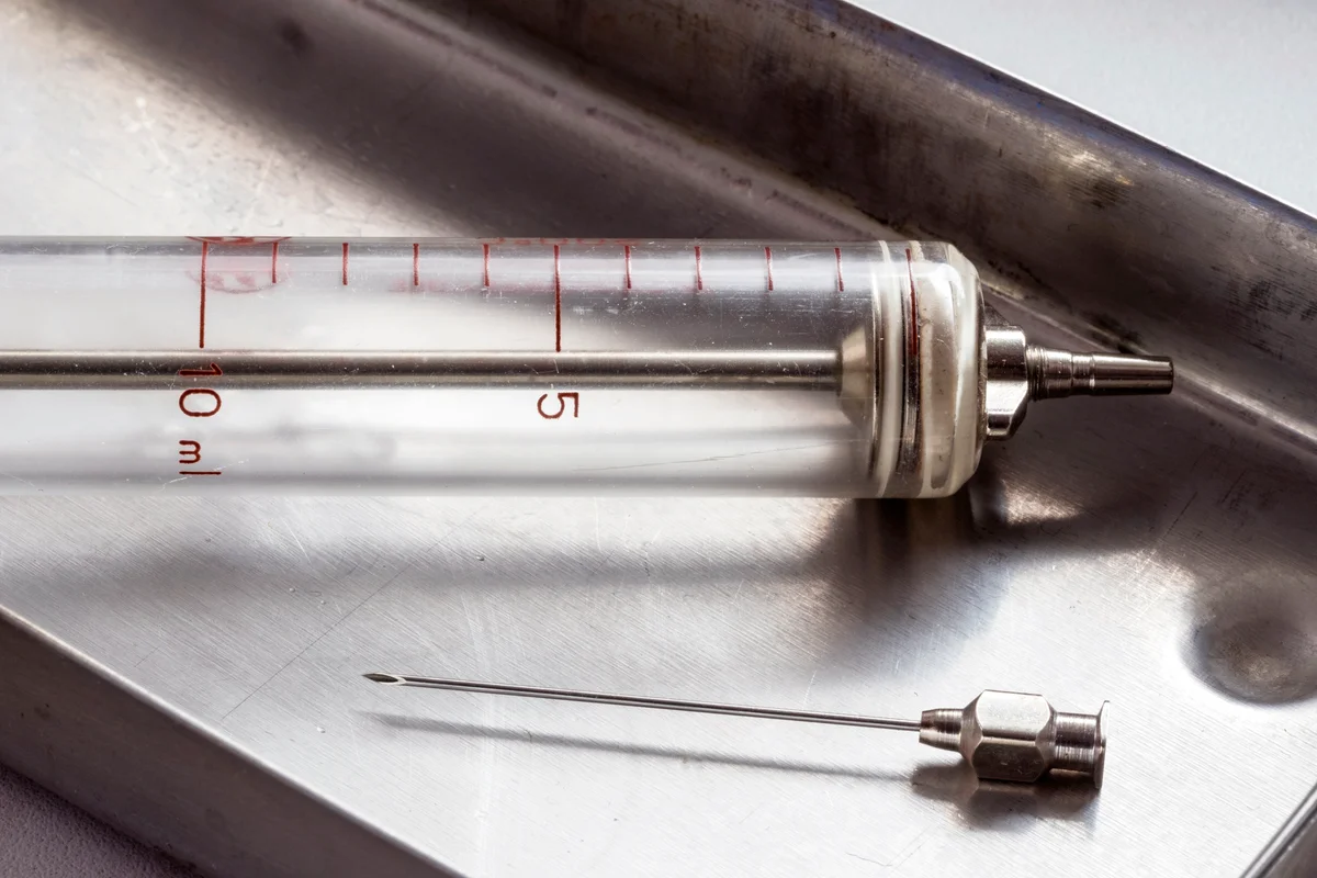 Vintage glass syringe on medical tray