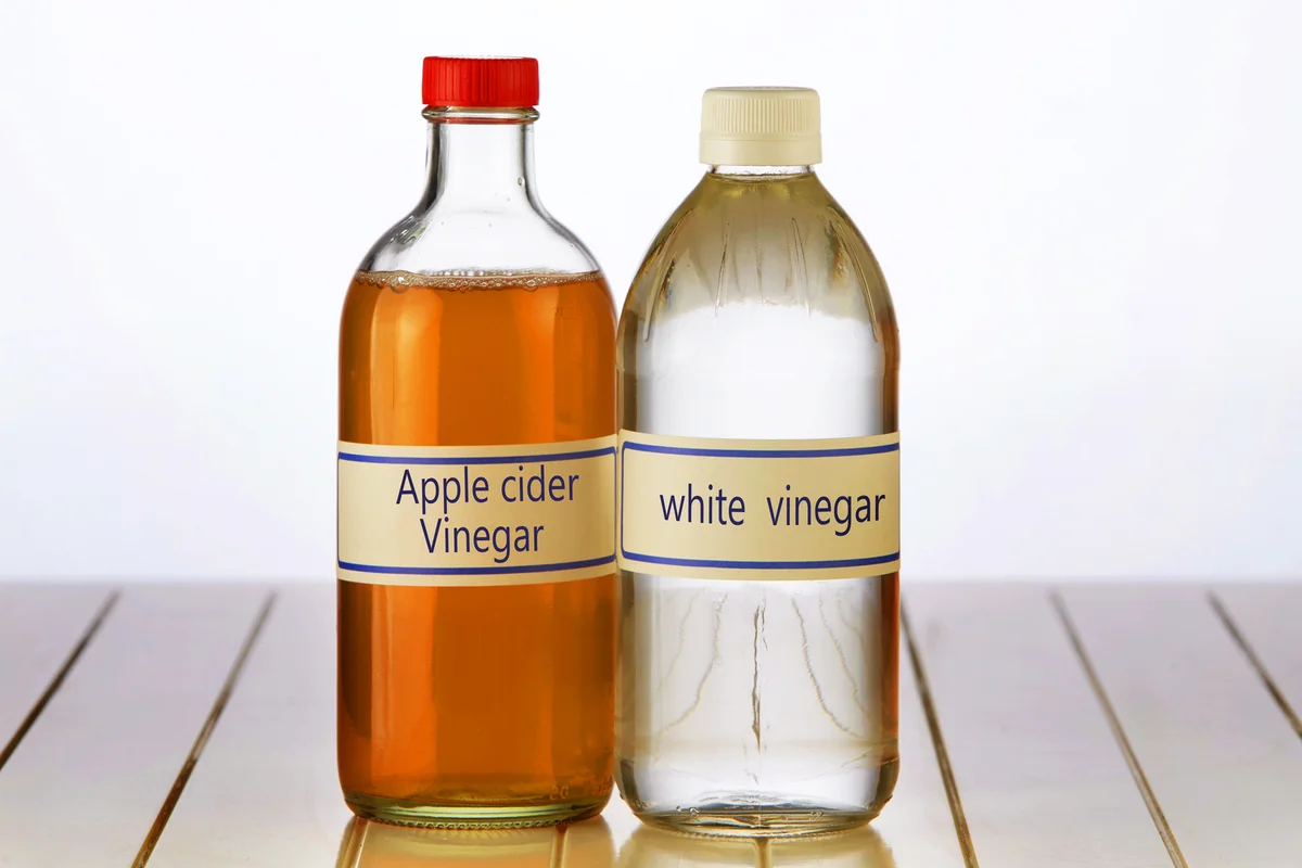 White vinegar and apple cider vinegar on table