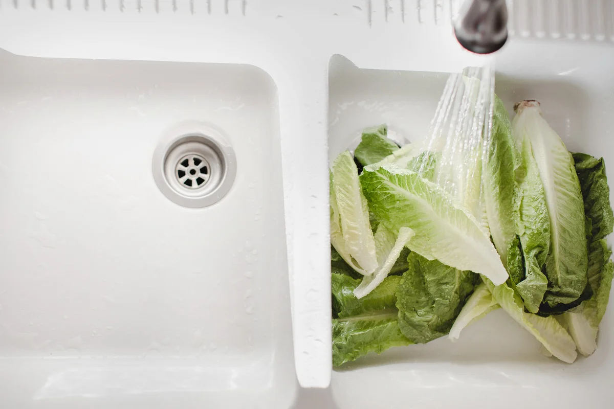 Water washing lettuce in a farmhouse sink