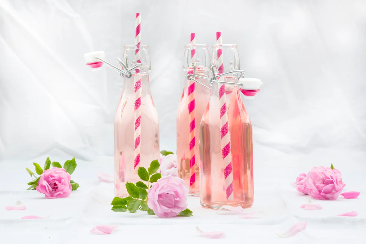 Rose punch in bottles with decorative pink and white straws