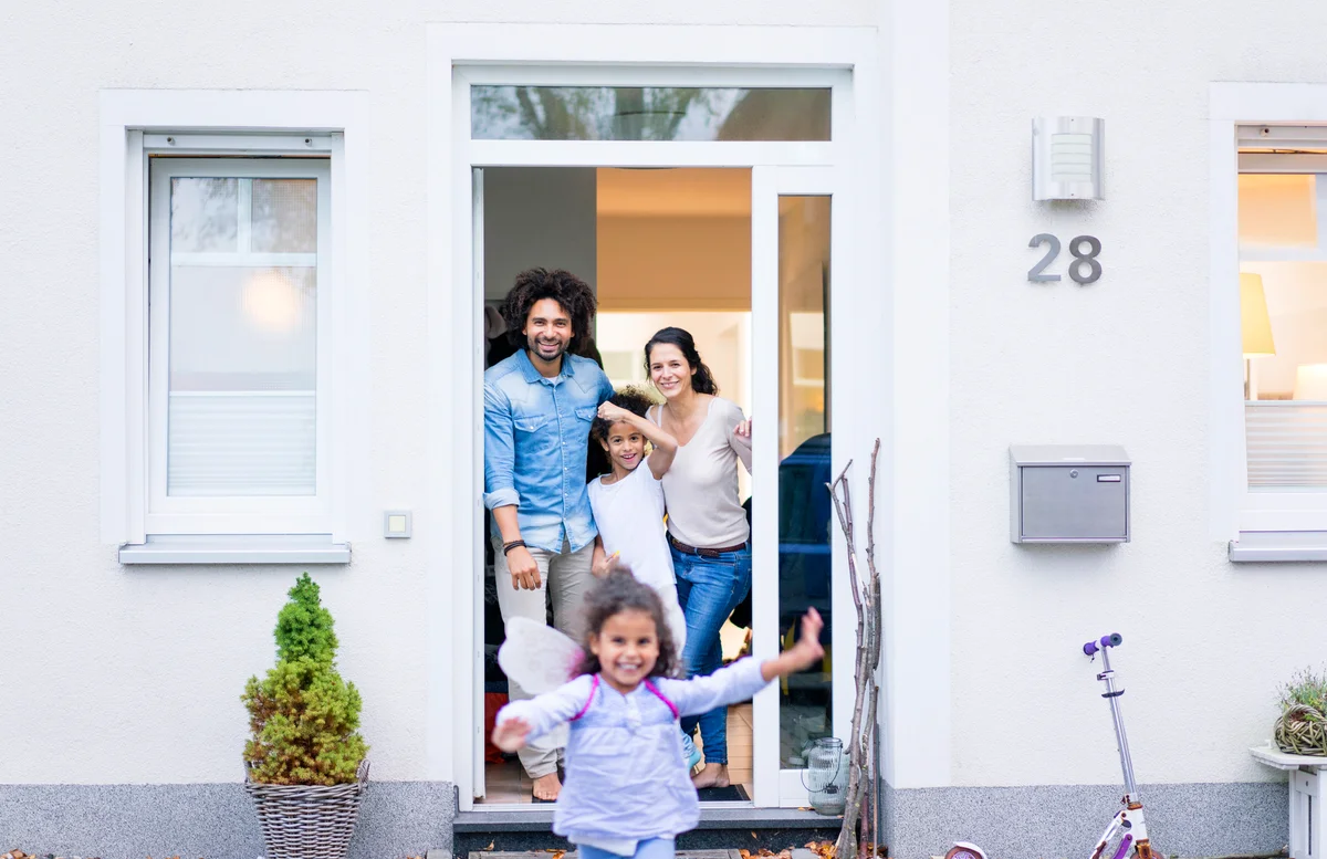 Laughing family waiting at the entrance of their home
