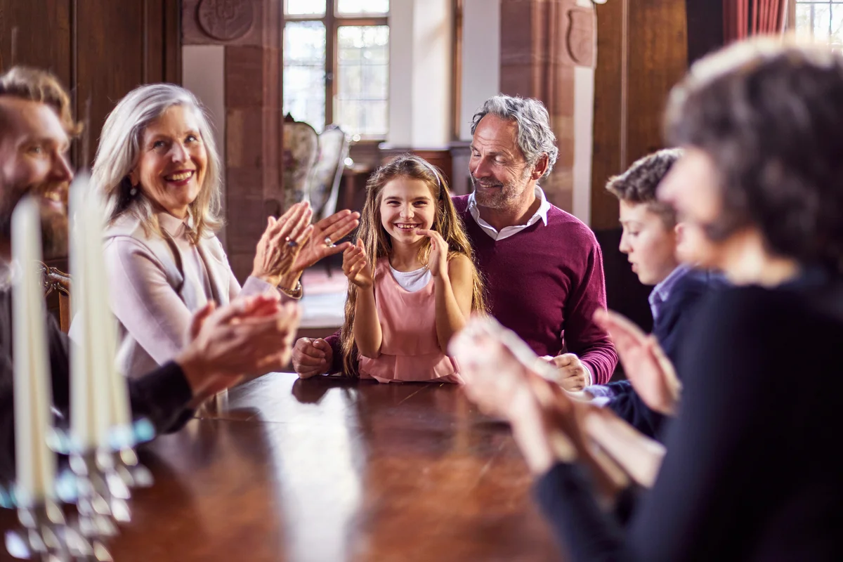 Happy family sitting around wooden table applauding