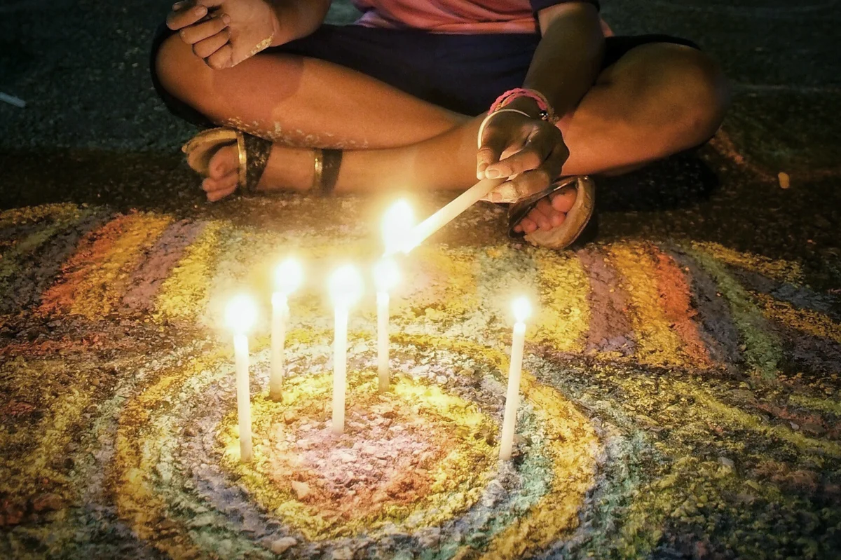 Woman Igniting Candles On Street At Night