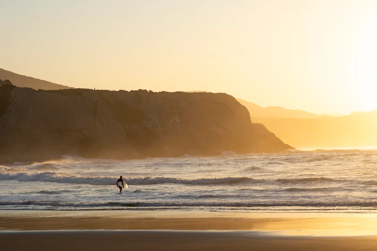 Surfer carrying surfboard into the ocean