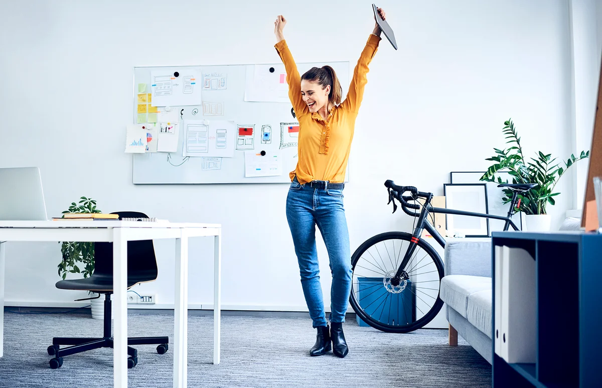 Happy young businesswoman cheering in office