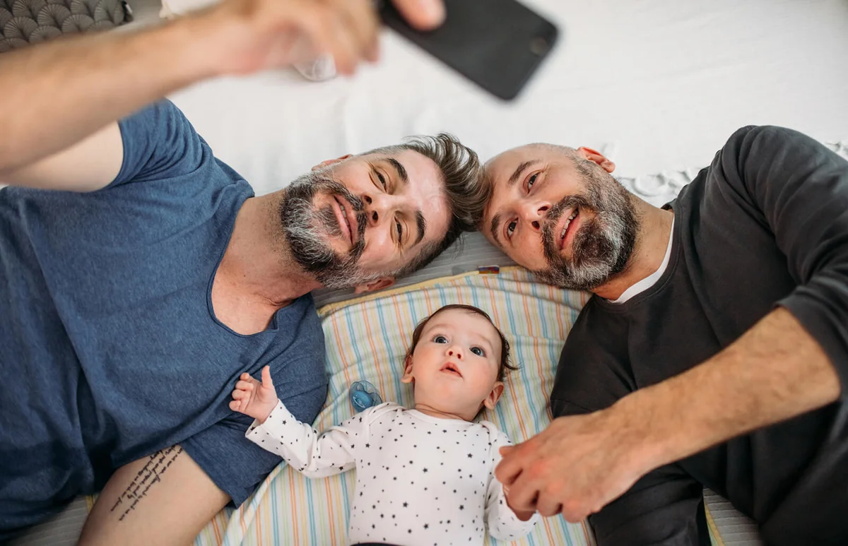 dads playing with their adopted baby in the bedroom