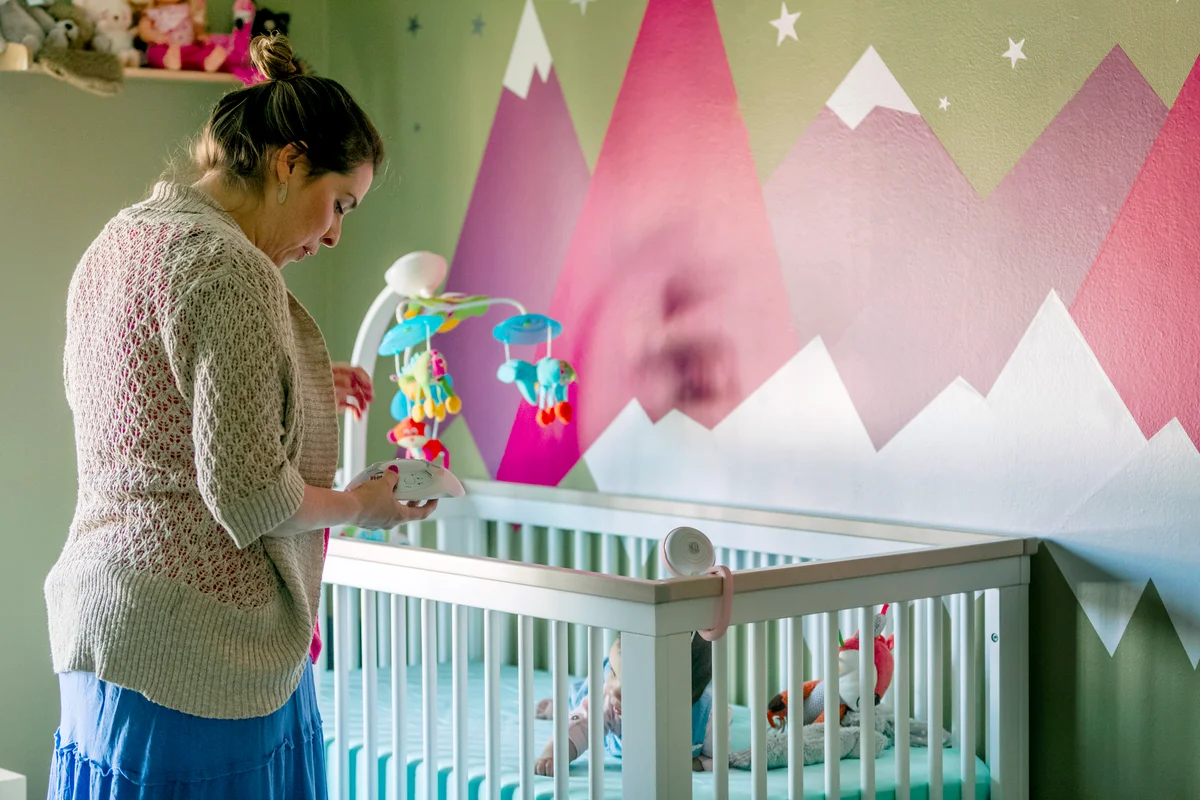 Mother checking at baby in the crib in Nursery room