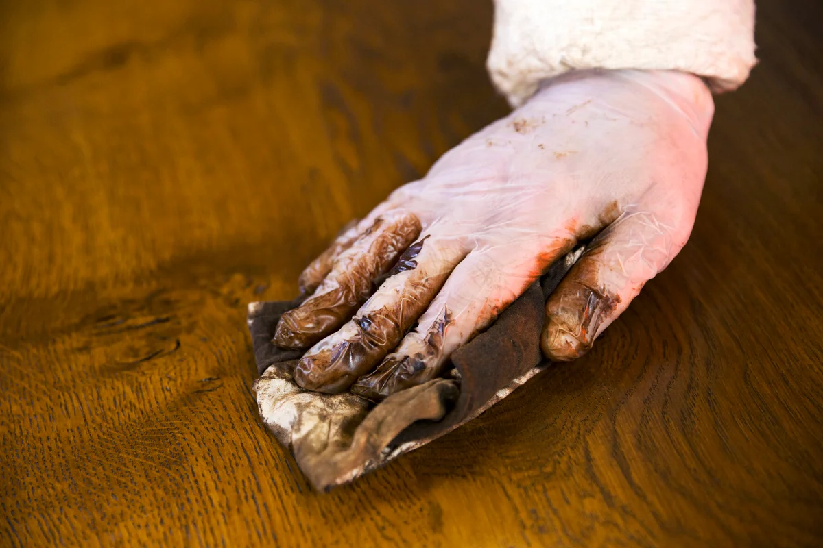 Carpenter wearing protective gloves, polishing a wooden surface