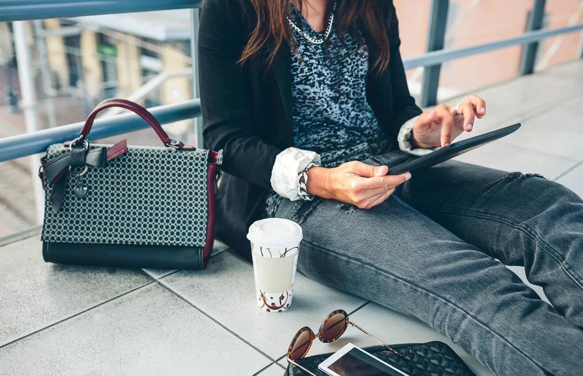 woman using tablet computer while sitting on footbridge