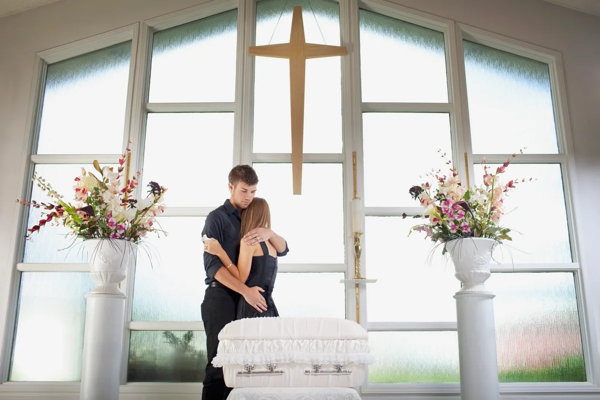 Grieving parents standing near a small casket