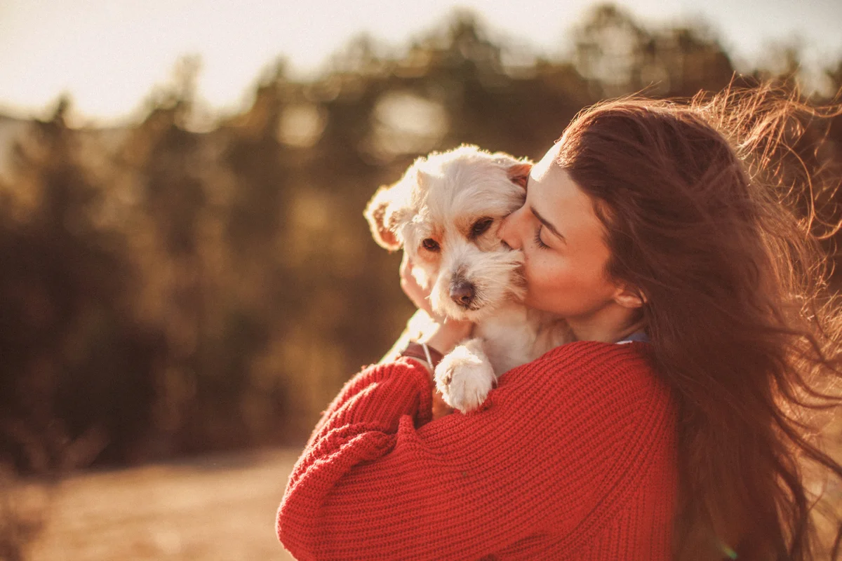 Woman hugging and kissing pet dog
